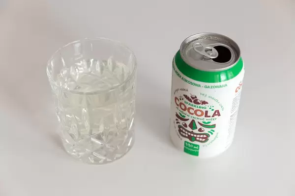 Weiße Cocola, polnischer Erfrischungsdrink mit natürlichem Kokosnusswasser in einer Dose, neben einem gefüllten Glas