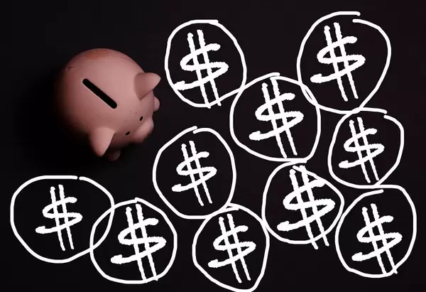 Weiße Dollarsymbole auf schwarzem Hintergrund, neben einem rosa Sparschwein aus der Sicht von oben