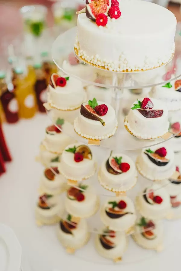 Weiße Minikuchen auf einem Tortentablett mit schicker Verzierung