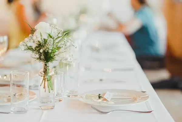 Weiße Rose in einer Glasvase in der Mitte eines Hochzeitstisches in Seitenansicht