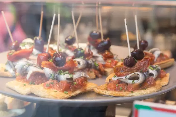 Weiße Sardellen auf Blätterteig mit Tomaten und braunen Kalamata-Oliven in Barcelona (Spanien)