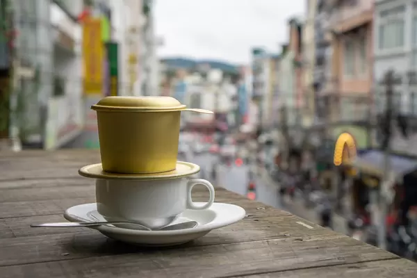 Weiße Tasse mit Löffel und Untertasse mit Stadtblick im Hintergrund Nahaufnahme