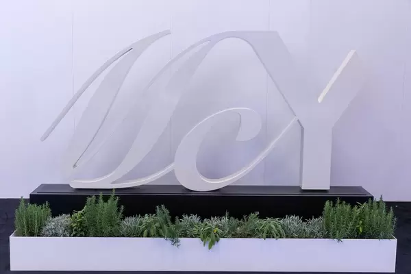 Weißes Logo von MCY (Monte Carlo Yachts) auf schwarzem Sockel mit Kakteen als Dekoration