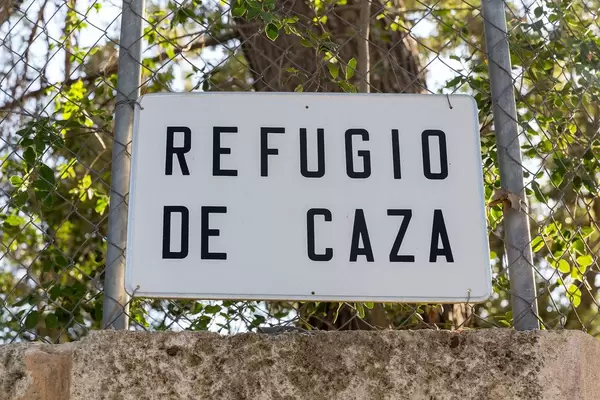 Weißes Schild auf Spanisch "Refugio de caza" auf Mallorca. Schutzgebiet, wo man nicht jagen darf