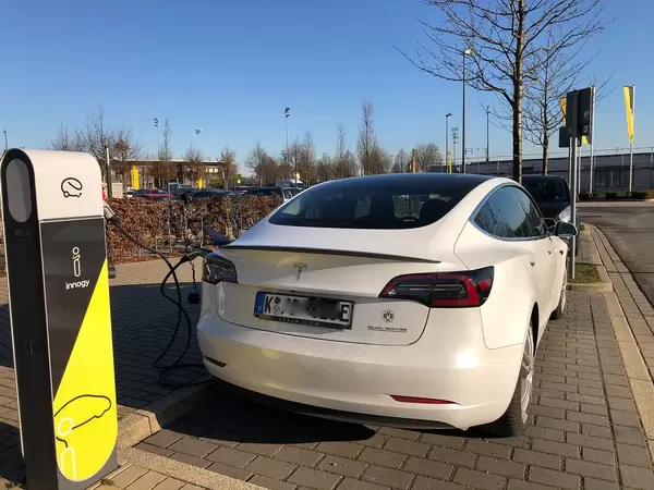 Weißes Tesla Fahrzeug wird bei einer Innogy Ladestation für Elektroautos geladen