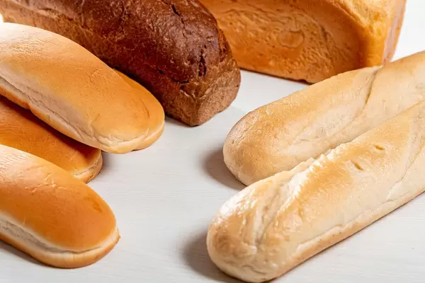 Weizenbrot, Weißbrot und Hot Dog-Brötchen, auf einem weißen Holztisch