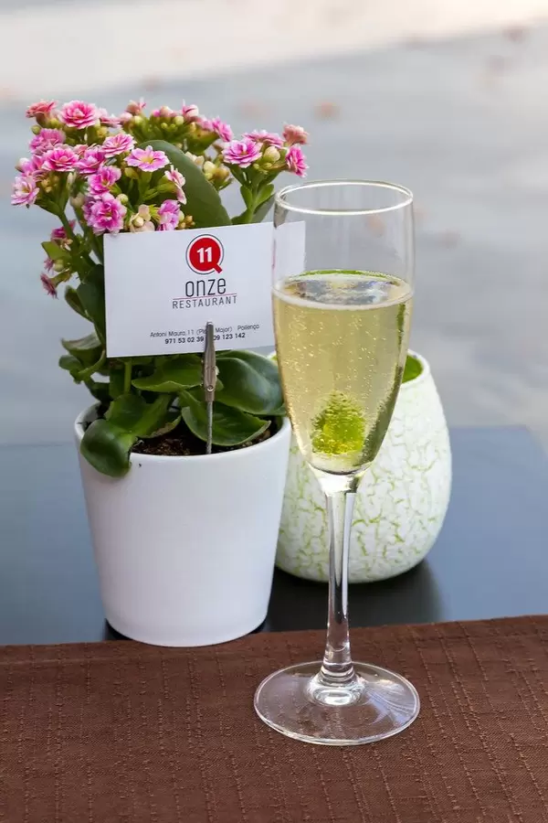 Welcome glass of prosecco and pot of flowers on the table at restaurant Q11 in Pollença, Mallorca