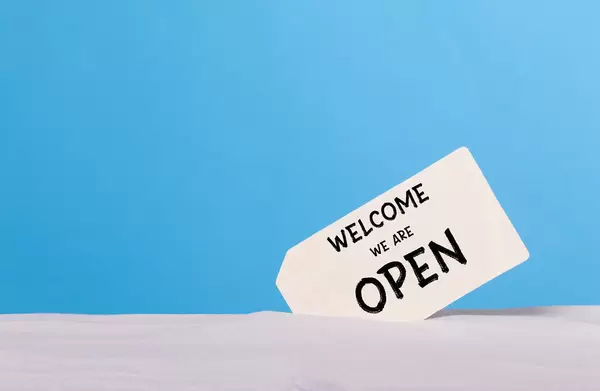 Welcome we are open sign on sandy beach