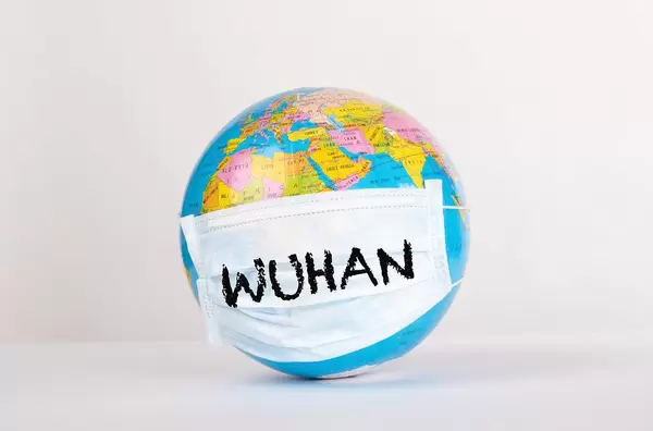 Weltkugel mit den Wort Wuhan auf einer Gesichtsmaske auf weißem Hintergrund