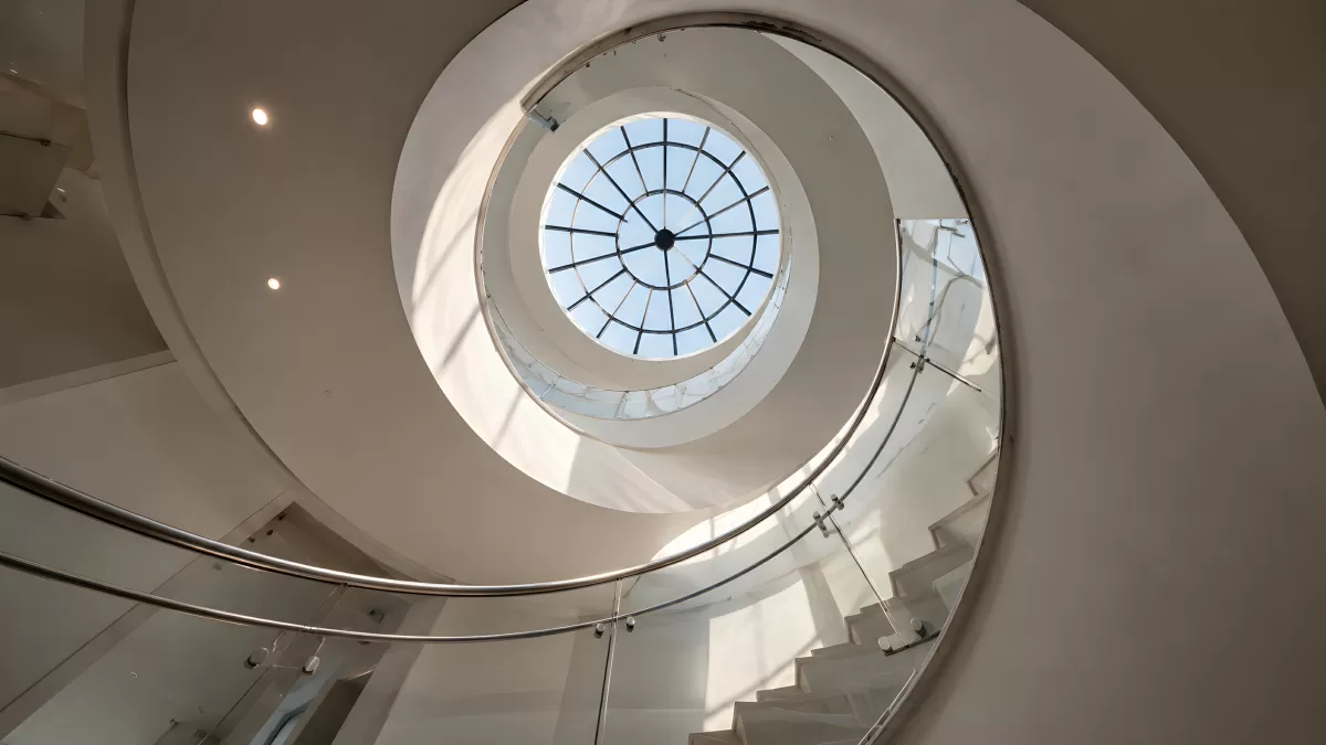 Wendeltreppe mit Glasgeländer und rundem Oberlicht