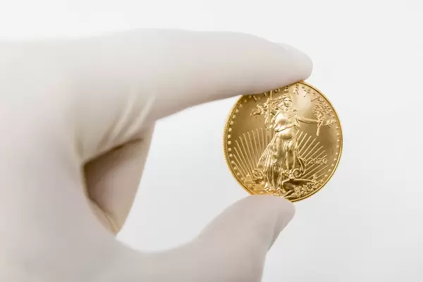 Wert der Coronakrise in den USA: Hand mit Einmalhandschuh hält eine Unze Gold