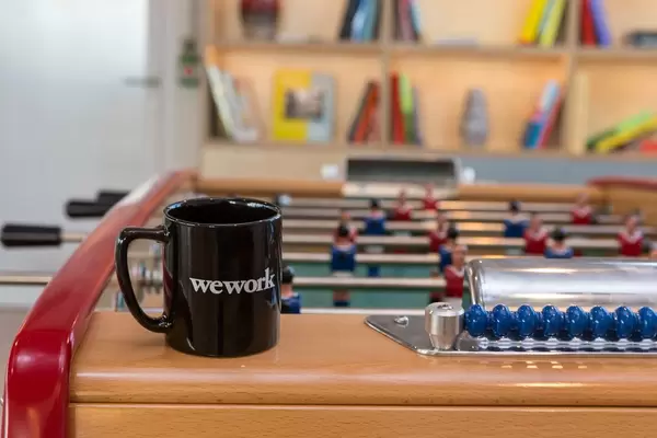 WeWork-Tasse auf einem Tischfußball im Gemeinschaftsbereich des Coworking Space in Köln