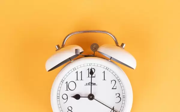 White alarm clock on yellow background