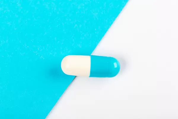 White and blue capsule on blue and white background, top view