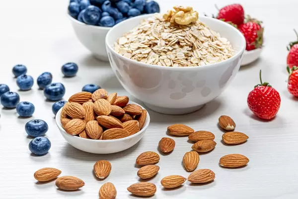 White bowls with fresh fruit, nuts and oatmeal