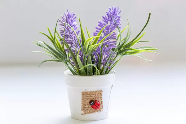White bucket with purple artificial flowers