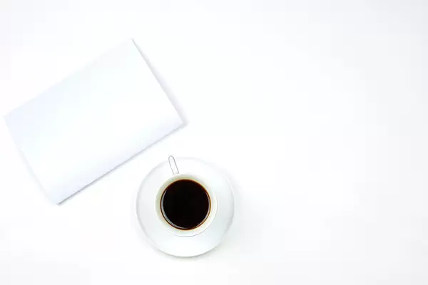 White business notepad with a cup of coffee on pure white background