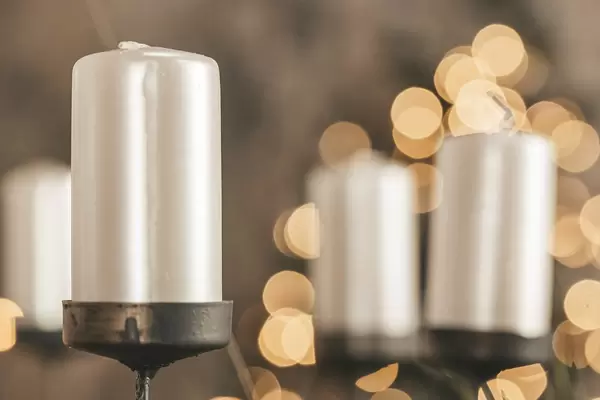 White candles on a golden bokeh background