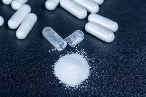 White capsules with powder and one open on a black background (Flip 2020)