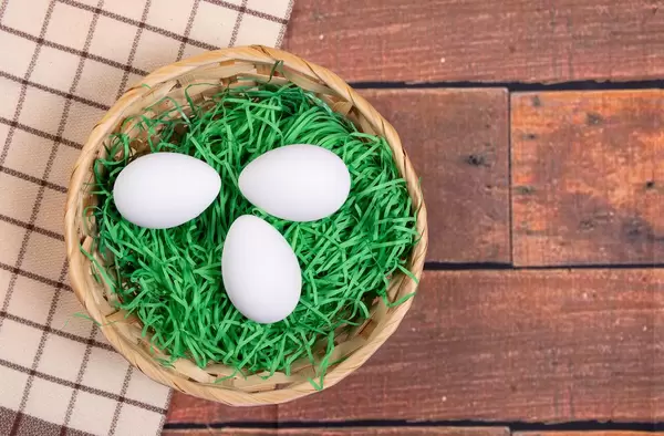 White chicken eggs in a basket on a wooden table