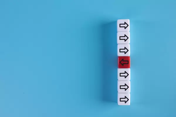 White cubes with right arrows and one red cube with left arrow on blue background