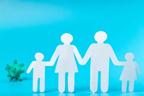 White family made of paper, behind a model of a virus on a blue background