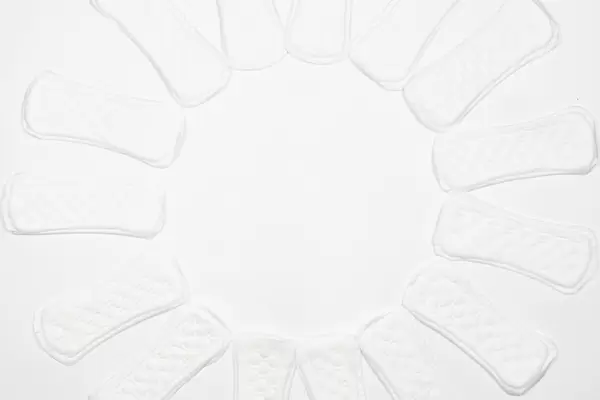 White feminine pads placed in circle form on white background
