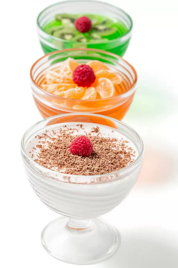 White, orange and green jelly in glass bowls on white background