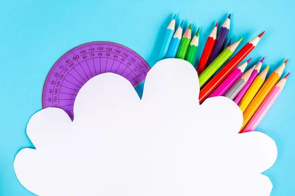 White paper cloud on a blue background with colored pencils and protractor