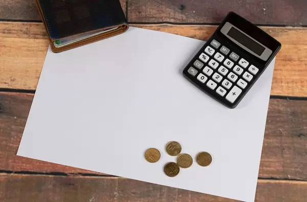 White paper on wooden dest with wallet and calculator