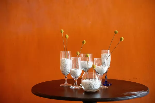 White Pebbles in Different Glasses on a Round Wooden Table as Decoration inside a Cafe