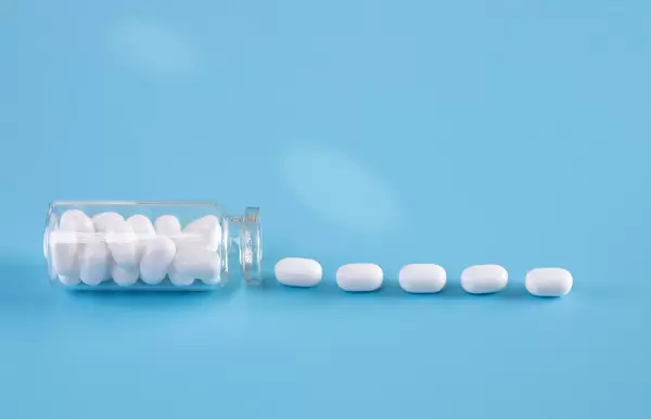 White pills in bottle on blue background