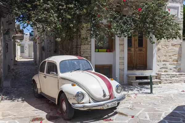 White-red Volkswagen Beetle classic car in an alley of the village of Chalki on Naxos, Cyclades, Greece