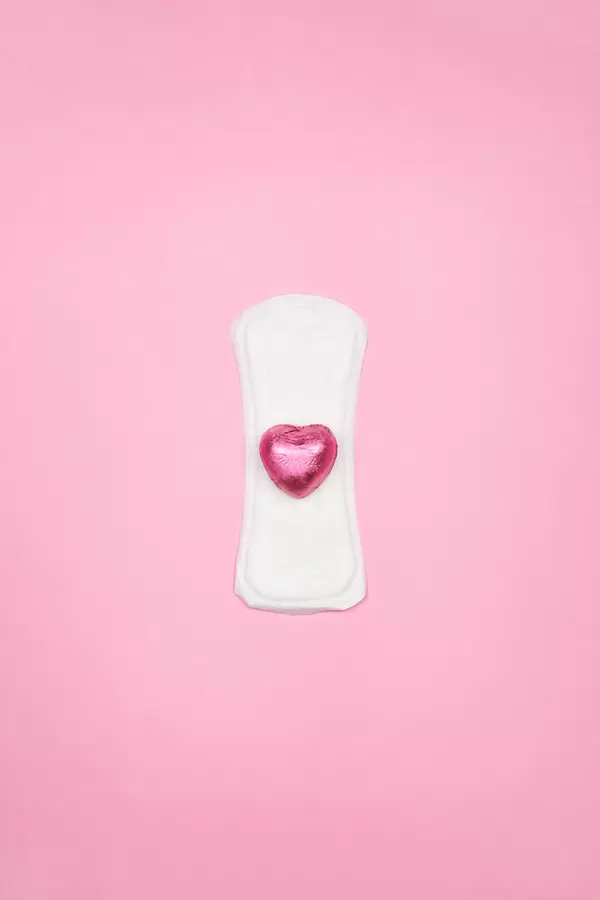 White sanitary napkin with a pink candy on bright color background