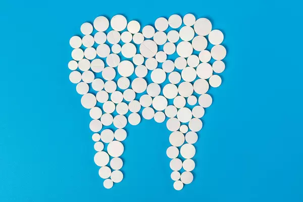 White tablets in the shape of a tooth on a blue background, the concept of healthy teeth