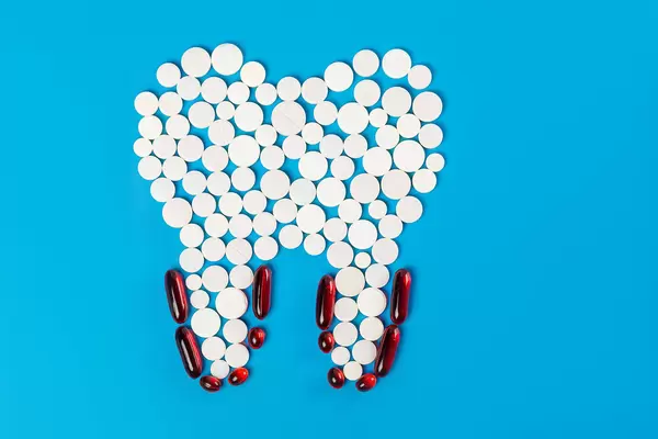 White tooth model made from pills and red capsules, concept of dental caries treatment