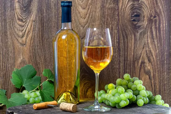 White wine with fresh grapes and corkscrew on brown wooden background (Flip 2019)