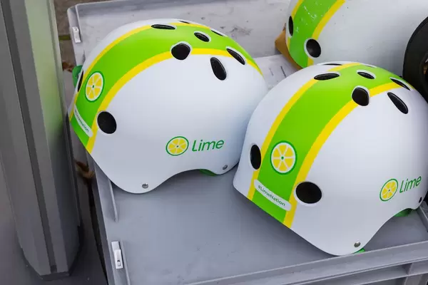 White, yellow and green helmets with the logo of the e-scooter sharing brand, Lime