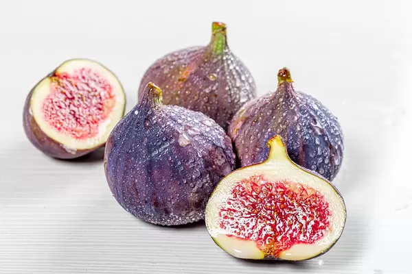 Whole and halves of fresh figs with water drops on white wooden background (Flip 2019)