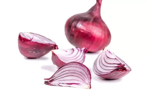 Whole and pieces of purple onion on a white background