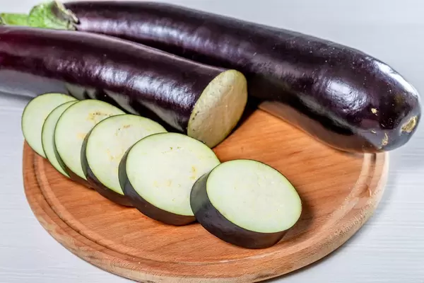 Whole and sliced ripe eggplant on the kitchen Board (Flip 2019)