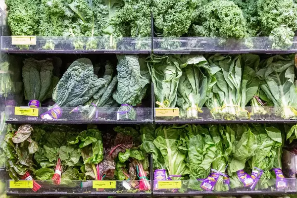 Whole Foods Supermarket shelf filled with green organic salad leaves, kale, red and organic rainbow chard