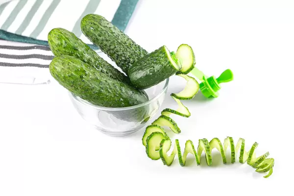 Whole fresh cucumbers in a glass bowl and cucumber spiral