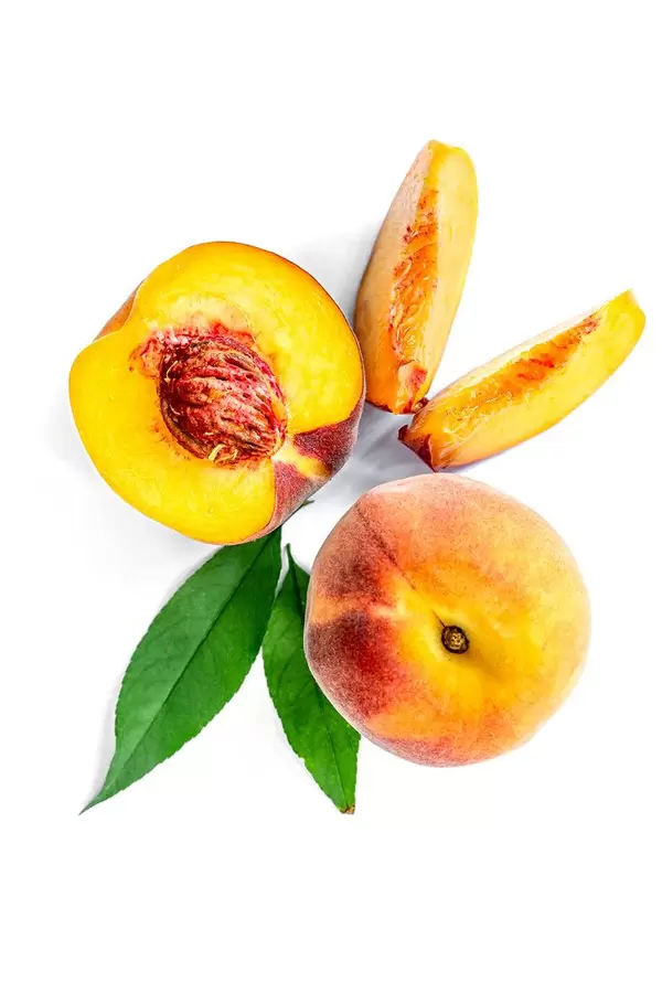 Whole, half and slices of peaches on a white background