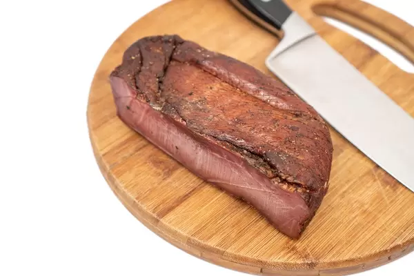Whole piece of Smoked Ham witk knife on the wooden board