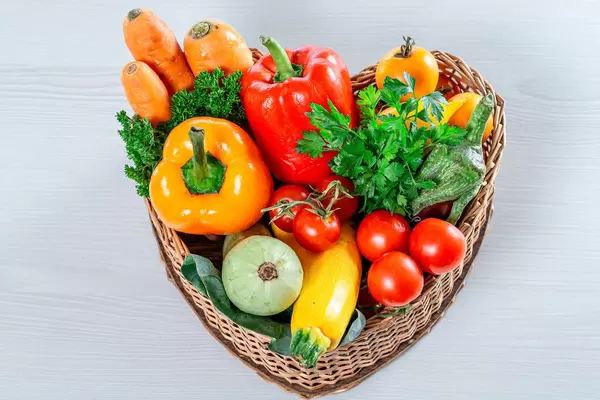 Wicker basket in the shape of a heart filled with fresh vegetables and herbs (Flip 2019)