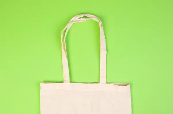 Wiederverwendbare Baumwolltasche für Einkäufe vor hellgrünem Hintergrund