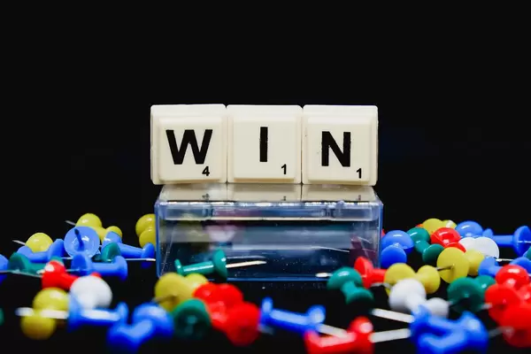 Win (Gewinnen) Text mit Reißzwecken auf schwarzem Untergrund