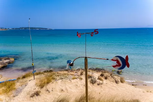 Wind chime with compass - direction indicator in the white sandy beach before the wide Aegean Sea
