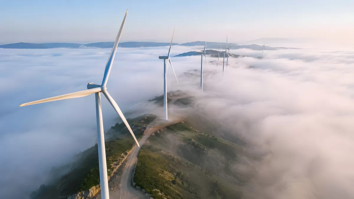Windräder über Wolkenmeer auf Bergrücken bei Sonnenaufgang